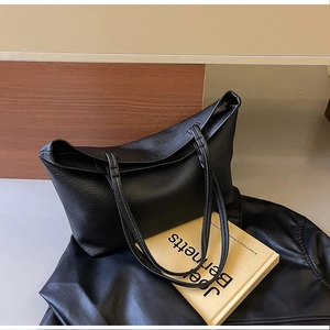 Detail of black large capacity tote bag with lychee texture leather and slim handles