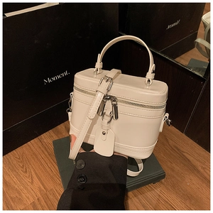 Detail der weißen glänzenden Box-Tasche mit Reißverschluss, Rundgriff und verstellbarem Riemen