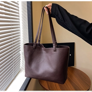 Detail of dark coffee litchi grain leather texture on large capacity tote bag