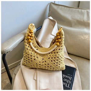Sac à main crochet beige avec poignées en perles de bois sur une veste beige