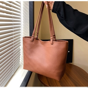 Detail of caramel faux leather tote bag showing rich pebble grain texture and slim straps