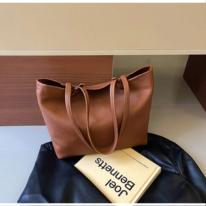 Detail of brown tote bag with pebble leather texture on a vintage leather jacket