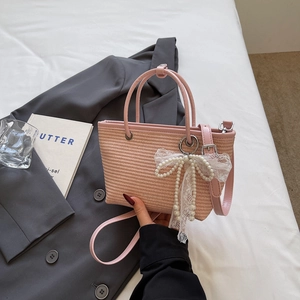Pink straw handbag with white lace bow and pearl charms for casual or vacation use