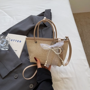 Chic beige straw tote bag with lace bow and pearl chain for casual vacation look