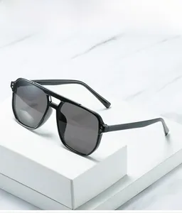 Detail of black double-bridge sunglasses with silver rivets on white marble background