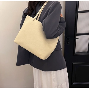 Detailed macro shot of the cream-white litchi grain texture on this large leather tote bag