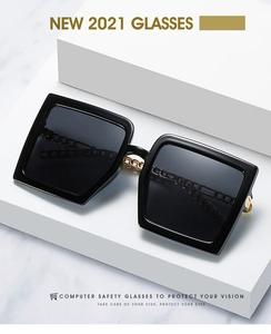 Detail of glossy black oversized sunglasses with elegant gold chain temple accents