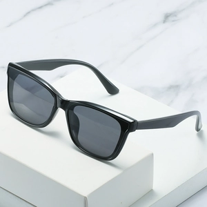 Classic small square black sunglasses with dark lenses displayed on a white podium