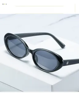 Detailansicht einer schwarzen ovalen Sonnenbrille mit glänzendem Rahmen auf weißem Podest