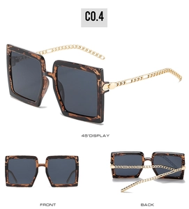 Detail showing oversized tortoise shell sunglasses with golden chain link temples and grey lenses