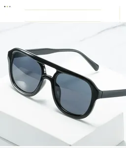 Nahaufnahme der schwarzen Vintage-Sonnenbrille mit Doppelsteg auf weißem Geometrie-Podest