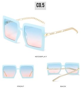 Detail view of large square sunglasses with light blue frames and gold chain temples