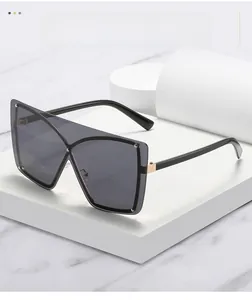 Detail of oversized sunglasses showing gradient grey lenses and decorative metal rivets