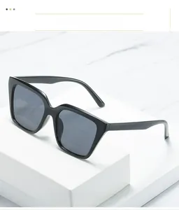 Detailed close-up of glossy black square sunglasses with dark lenses on a marble base