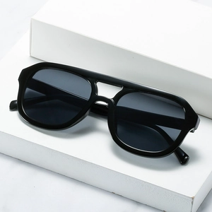 Retro-Sonnenbrille mit Doppelsteg in Schwarz auf einem minimalistischen weißen Ständer