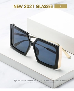 Détail de la charnière en métal doré sur de larges lunettes de soleil carrées noires