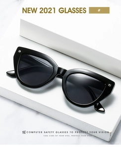 Detail view of black cat-eye sunglasses with silver square studs on marble surface