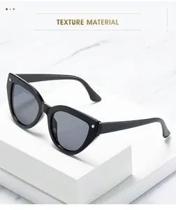 Detail shot of black cat-eye sunglasses with silver metal studs on a marble base