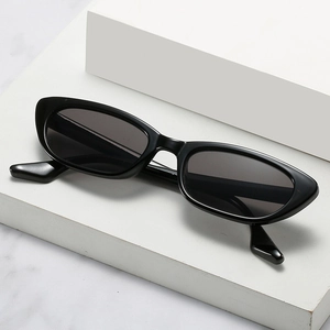 Lunettes de soleil œil de chat noires avec verres foncés sur socle minimaliste