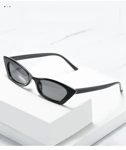 Close-up of black cat-eye sunglasses on a white geometric stand with marble background