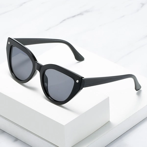 Fashionable cat-eye sunglasses in black frame with silver metal studs on marble background