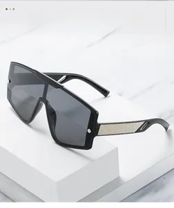 Détail de lunettes de soleil noires surdimensionnées avec verres monoblocs et branches crème