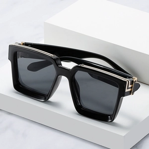 Modern oversized black square sunglasses with gold metal accents on a marble background