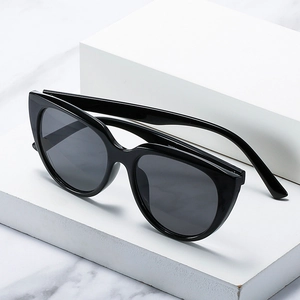Classic black cat eye sunglasses with dark grey lenses on white minimalist pedestals