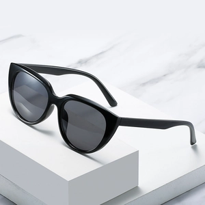 Classic black cat-eye sunglasses with dark lenses on a white marble surface display