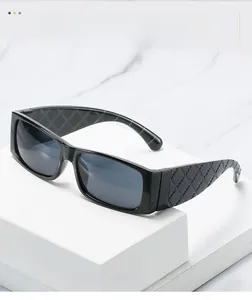 Details einer schwarzen rechteckigen Sonnenbrille mit gesteppten Bügeln und grauen Gläsern