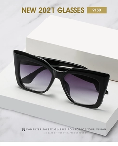 Detail view of oversized cat-eye sunglasses with thick black frame and purple gradient lens
