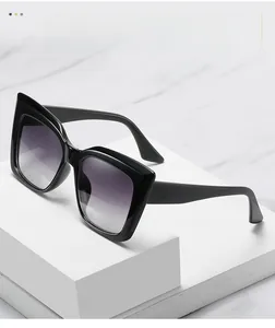 Close-up of thick black cat-eye frames with gradient lenses on a marble display