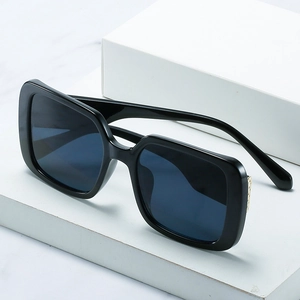 Classic black oversized square sunglasses with gold metal accents on white marble