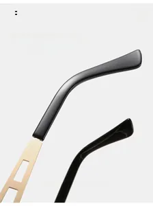 Detail of curved black sunglasses legs with ornate gold metal hollowed-out hinges