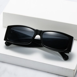 Retro-Rechteck-Sonnenbrille mit schwarzem Rahmen und strukturierten Bügeln auf Marmor