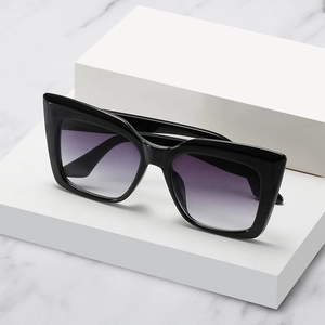 Oversized cat-eye sunglasses with glossy black frames and purple gradient lenses