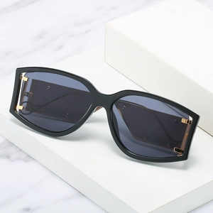 Lunettes de soleil oversize noires avec verres foncés et détails dorés sur des marches