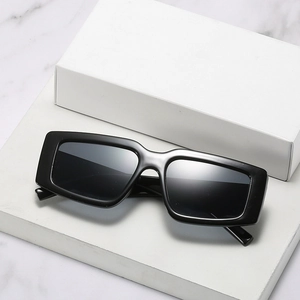 Lunettes de soleil carrées noires modernes avec verres foncés sur surface en marbre