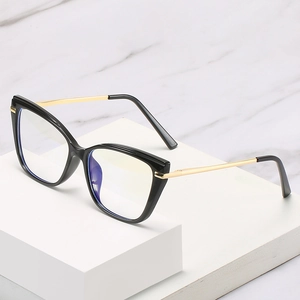 Lunettes œil-de-chat TR90 modernes avec monture noire et branches dorées sur fond marbre