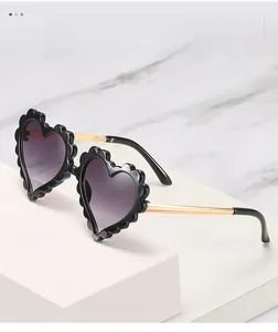 Detail of heart-shaped sunglasses with scalloped frames and golden metal temples