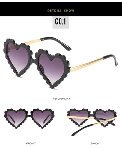 Detail view of scalloped heart-shaped sunglasses with black frames and gradient purple lenses