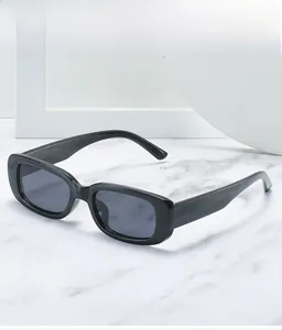 Detail view of glossy black rectangular sunglasses for kids on a marble surface