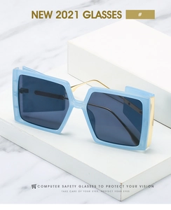 Detail of square blue glasses with translucent frames and gold metal accents on marble