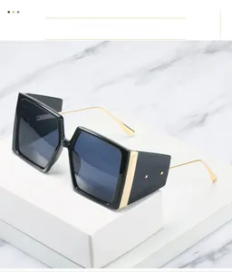 Detail of square black sunglasses featuring elegant gold metal trim and textured temples