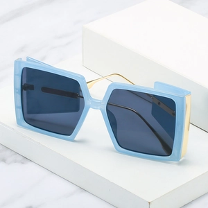 Light blue square oversized sunglasses with gold metal temples on marble background