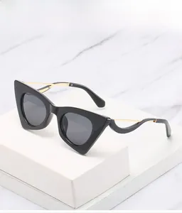 Détail des lunettes œil-de-chat avec monture noire et branches dorées ondulées