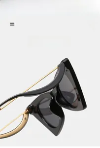 Détail de lunettes de soleil œil-de-chat avec monture noire et branches dorées