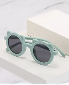 Detail of round mint green bear ear sunglasses on minimalist marble background