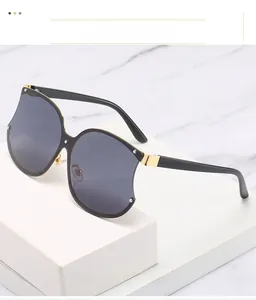 Détail de lunettes de soleil oversize avec branches en acétate noir et charnières dorées