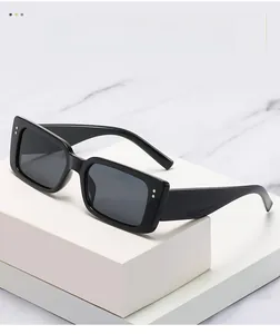 Detailaufnahme der schwarzen rechteckigen Sonnenbrille mit silbernen Nieten auf Marmor